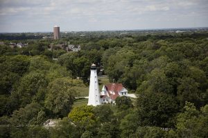 An aerial view of the North Point Lighthouse shows its place in Lake Park, with hints of the contemporary cityscape in the background. 