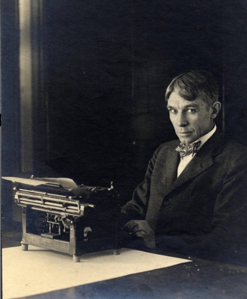 Photograph of Carl Sandburg sitting with his typewriter at his home in Illinois, circa 1917-1918.