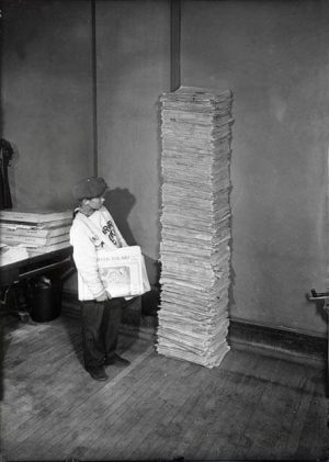 A young Kruyer Polski newspaper carries stands next to a stack of the 40th anniversary edition of the paper in 1928. The paper began in 1888 and was published until 1962.