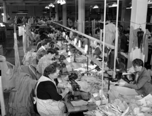 1945 photograph of women employed as garment workers at a factory located in the Mayer Building. 