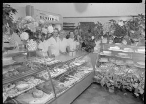 Women working for the Royal Baking Company, located on South 9th Street, stand behind display cases of baked goods in 1940. 