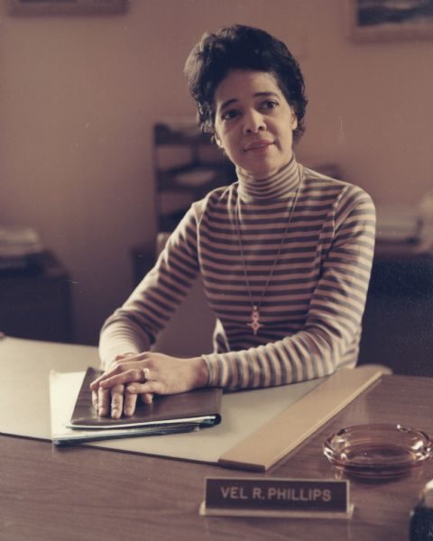 Renowned for her civil rights activism and historical status as Milwaukee's first alderwoman and African American on the city's Common Council, a younger Vel Phillips sits behind her desk.