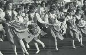 A group of six girls in traditional costumes dance at Greek Fest in 1984. Greek Fest is hosted by the Greek Orthodox Church of the Annunciation to celebrate Greek culture and community in Milwaukee. 