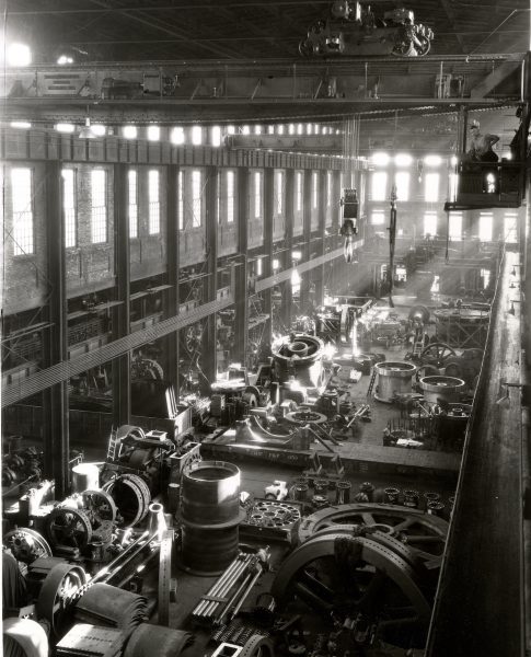 Photograph of an Allis-Chalmers work bay scattered with coiled metal sheeting taken in 1930.