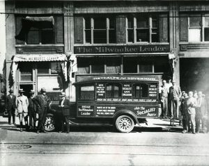 Men stand outside the office for the Milwaukee Leader in 1932. The paper's delivery truck is covered with messages promoting the Socialist Party. 