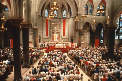 Photograph of a gathered congregation standing for mass held at Church of the Gesu. 