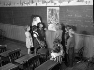 Photograph of a nun teaching a small group of children at St. Francis School in 1945.