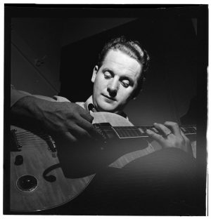 A younger Les Paul looks down at his guitar in this photograph from 1947. 