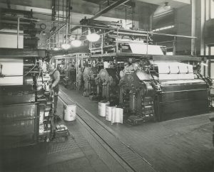 Men pass newspaper for the Milwaukee Journal through presses  in this 1947 photograph. 