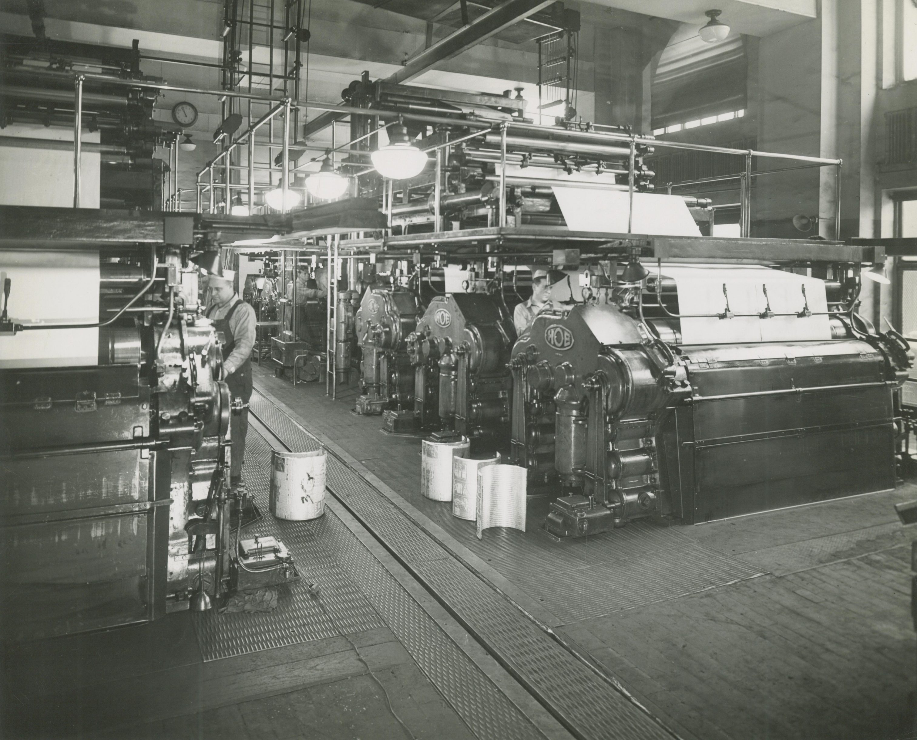 Men pass newspaper for the Milwaukee Journal through presses  in this 1947 photograph. 