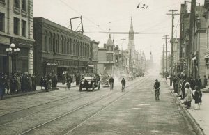 This 1914 photograph shows West Mitchell Street's use by cars and bicycles, as well as streetcars and pedestrians.